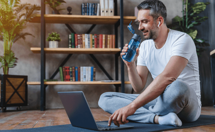 Man sitting after workout drinking from water bottle