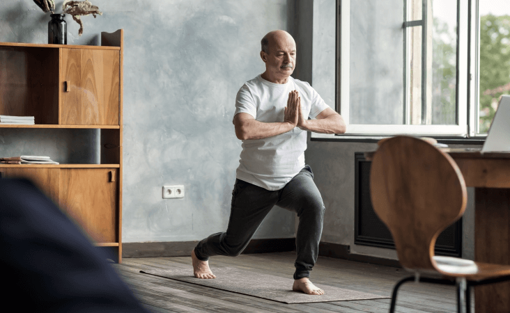 Older man holding yoga pose in living room